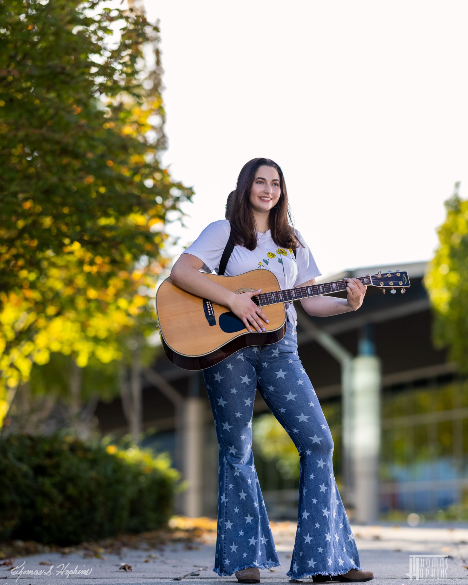 Outdoor senior portrait of a young musician with a guitar