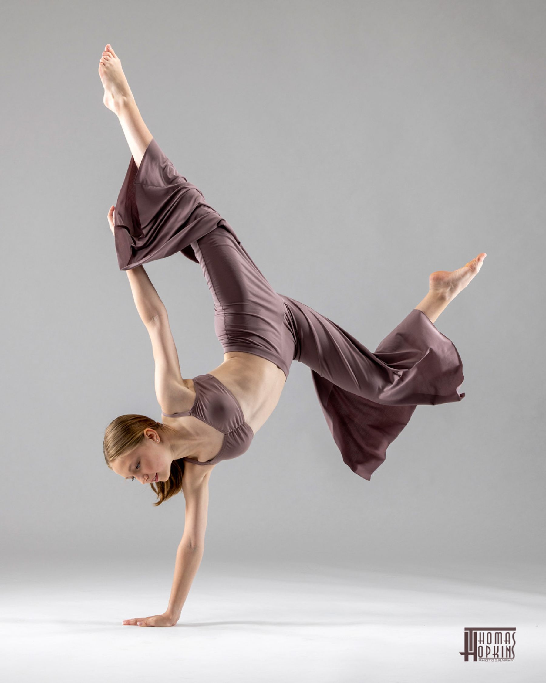 Dancer balancing on one hand with flowing fabric