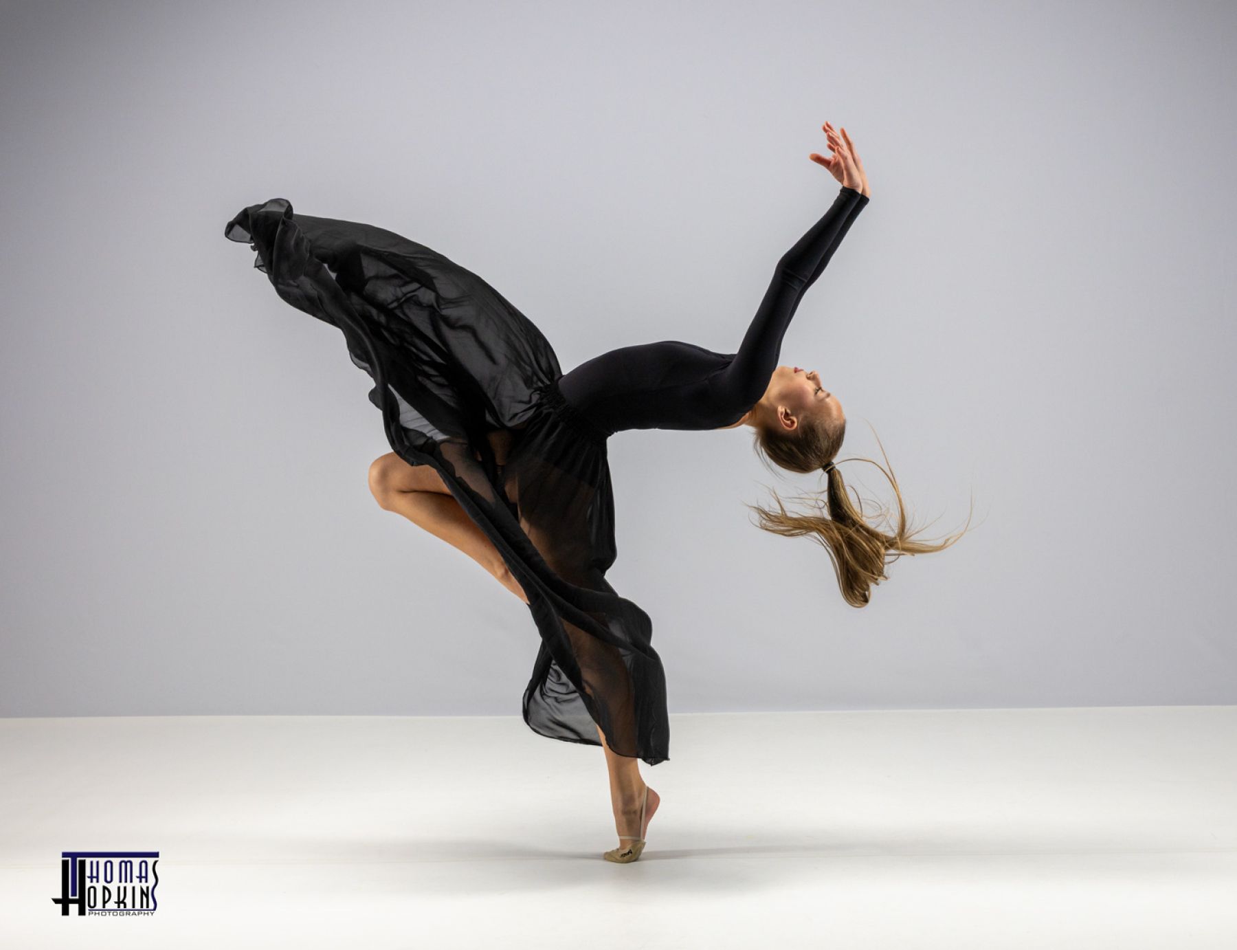 Dancer balancing on one hand with flowing fabric