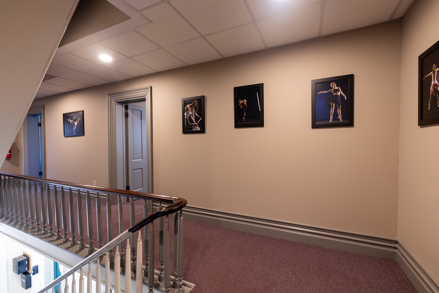 Second-floor hallway with framed photography and stair railing